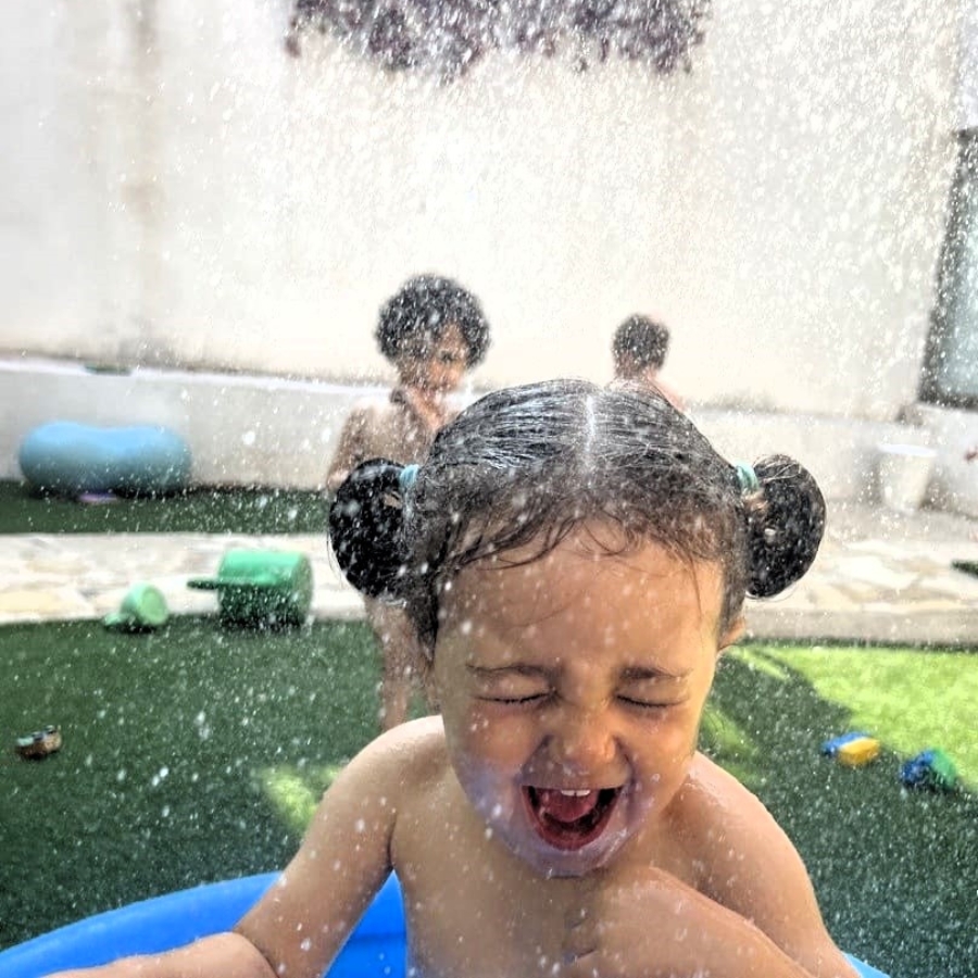 niños jugando con agua y riendo en jardín infantil