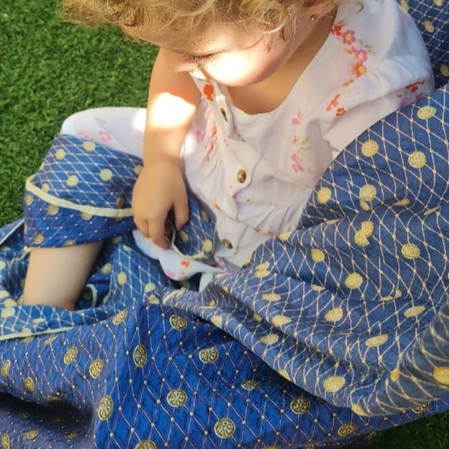 niña sentada con mantita y con sol en la cara